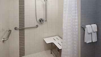 Un espace douche équipé d’un pommeau de douche à main, d’un pommeau de douche fixé au mur et d’une barre d’appui.