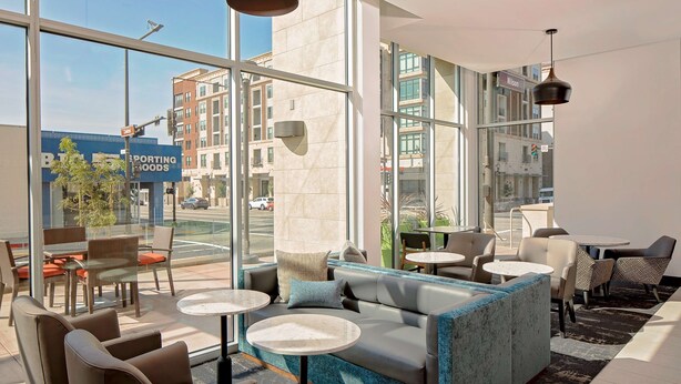 Un espace de détente intérieur moderne, doté de canapés en cuir, de tables rondes et de grandes fenêtres donnant sur la rue.