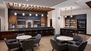 Un espace bar moderne avec des sièges, un comptoir et un distributeur automatique de boissons.