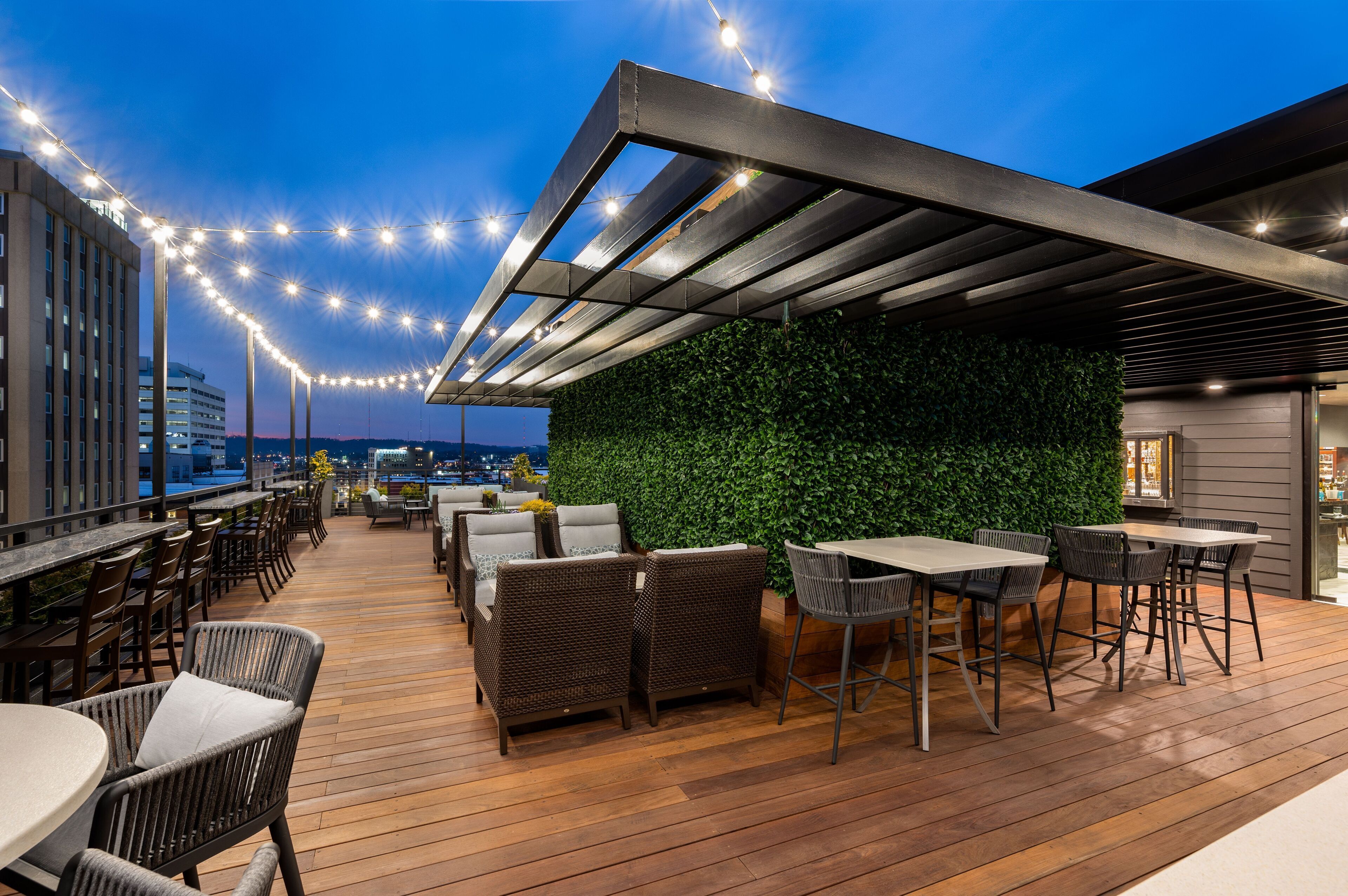An outdoor patio with wooden flooring, wicker furniture, and string lights.