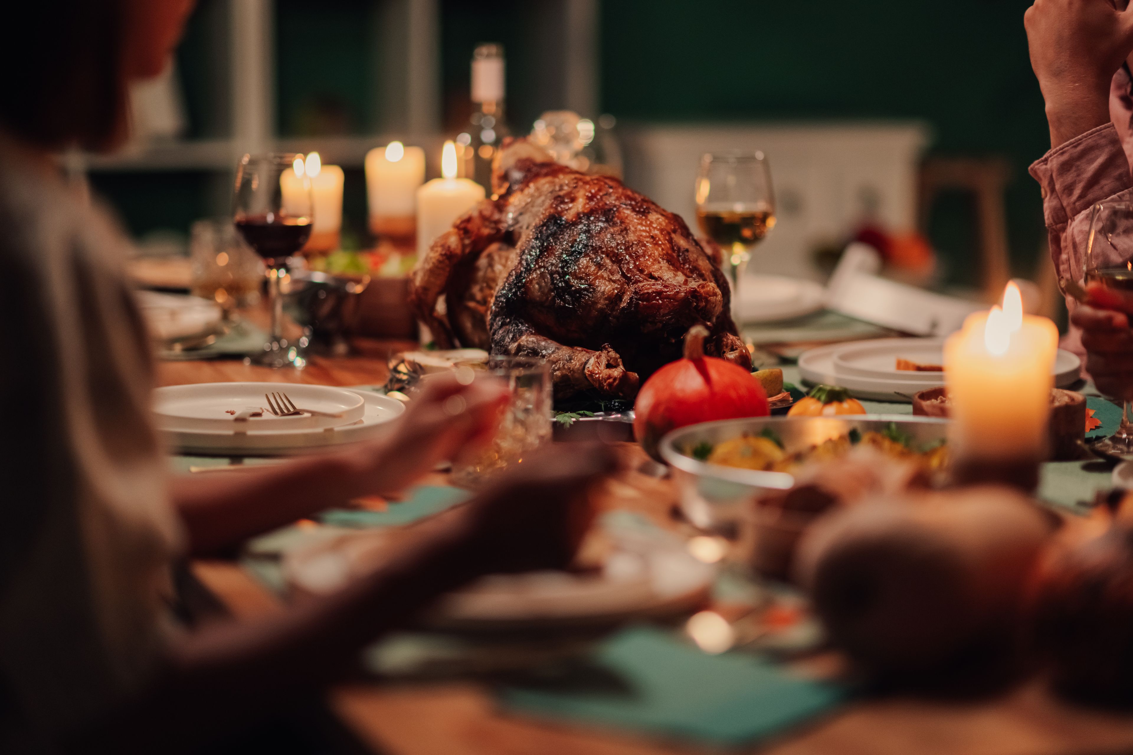 Een eettafel met een gebraden kalkoen, kaarsen en borden met eten.