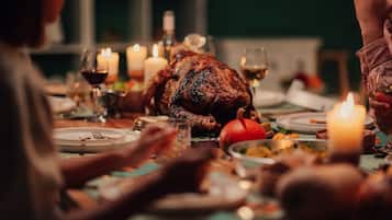 Een eettafel met een gebraden kalkoen, kaarsen en borden met eten.