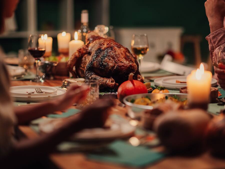 Een eettafel met een gebraden kalkoen, kaarsen en borden met eten.