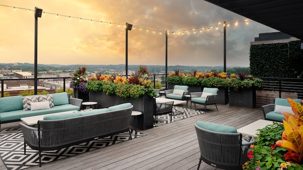 A rooftop patio with outdoor seating, string lights, and a view of the cityscape. - Hyatt Place Knoxville Downtown (Knoxville)