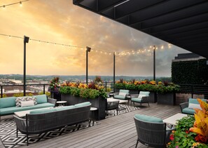 A rooftop patio with outdoor seating, string lights, and a view of the cityscape. - Hyatt Place Knoxville Downtown (Knoxville)