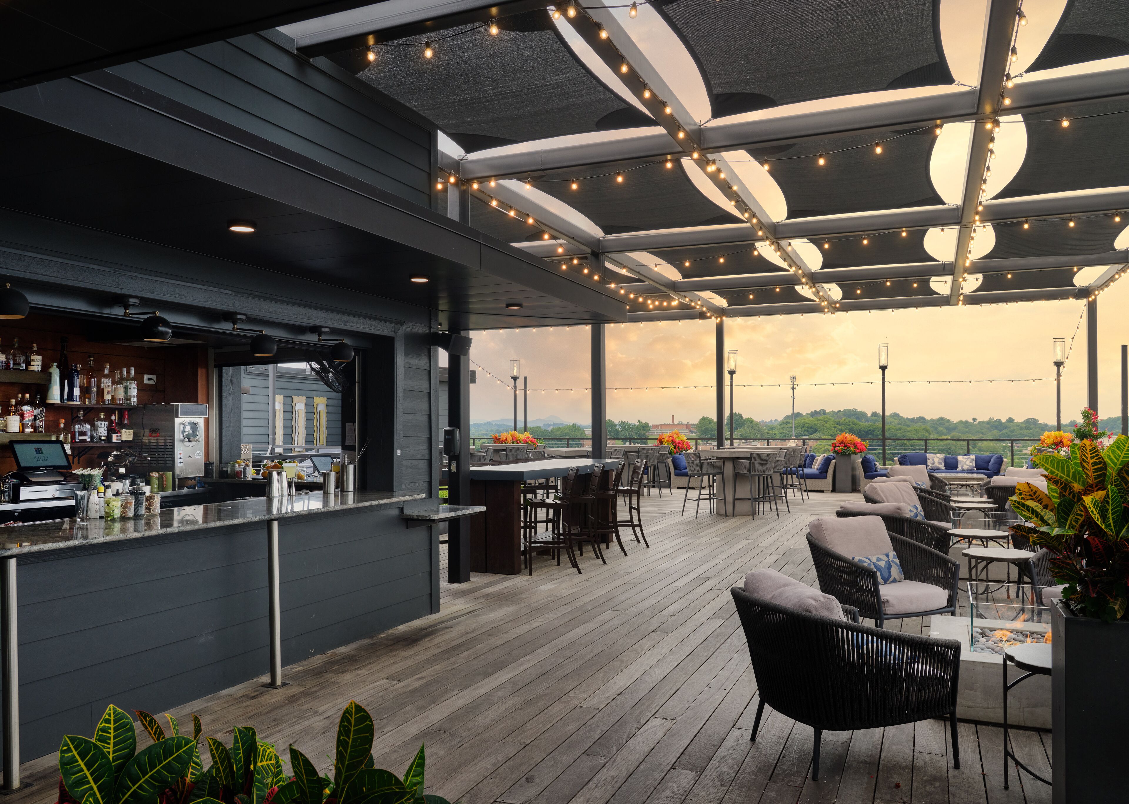 An outdoor bar area with a counter, seating, and string lights.