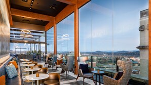 A modern lounge area with seating and tables, large windows offering a city view. - Hyatt Place Knoxville Downtown (Knoxville)
