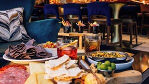 A bar area with a variety of food and drinks, including a tray with cheeses, meats, and a drink with a lemon slice. - Hyatt Place Knoxville Downtown (Knoxville)