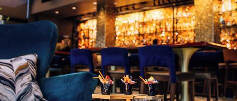 A bar area with a variety of food and drinks, including a tray with cheeses, meats, and a drink with a lemon slice.