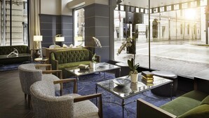 A modern lobby with a green sofa, wicker chairs, a glass coffee table, and a large window offering a view of the street. - Hyatt Place Knoxville Downtown (Knoxville)