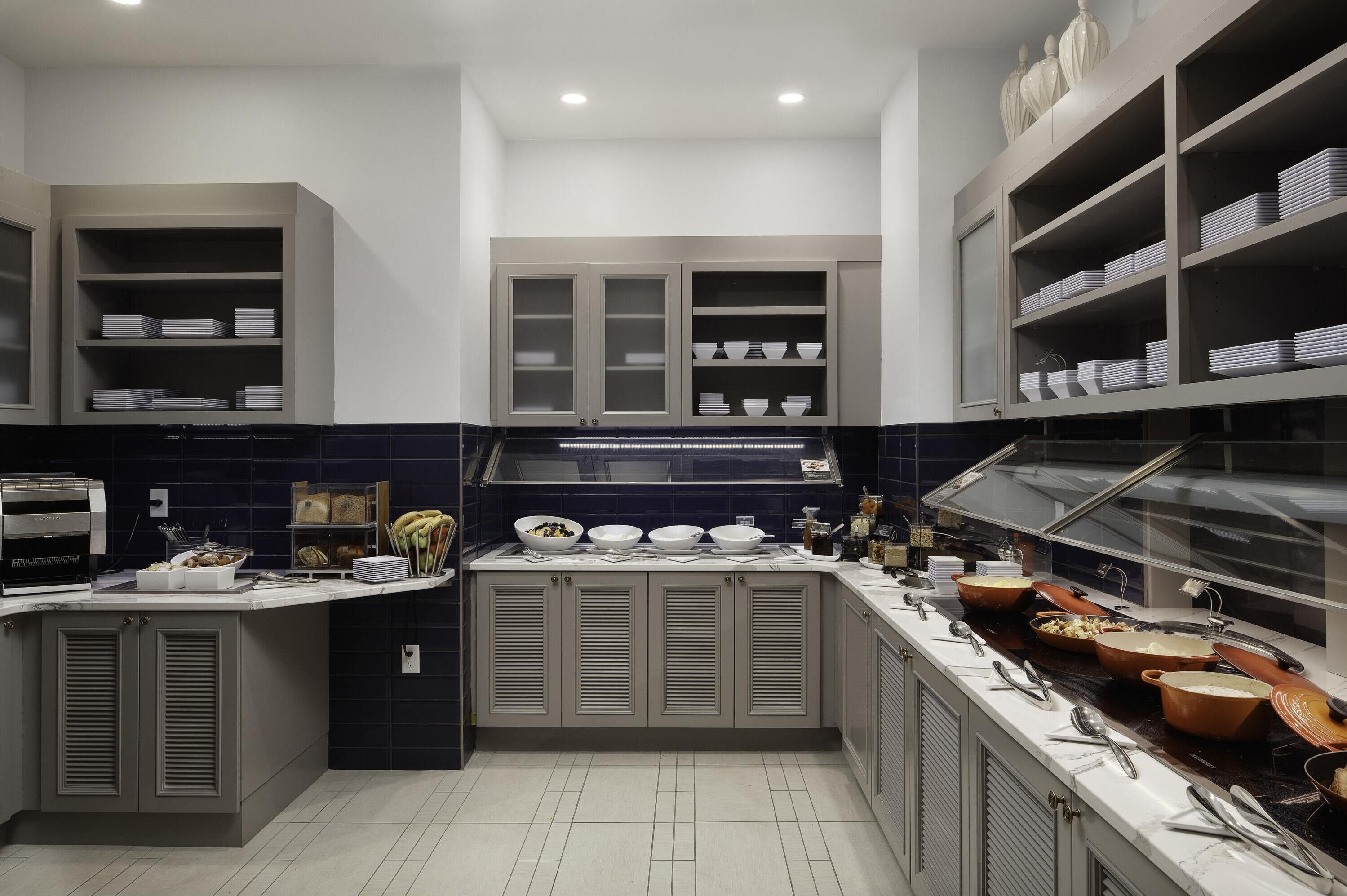 A modern kitchen with built-in cabinets, a buffet counter with food items, and a glass display case.