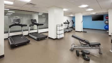 A gym with treadmills, a bench press, and dumbbells.