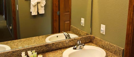 A bathroom with two sinks, a large mirror, and a towel rack with a bow.