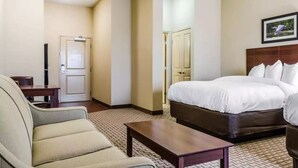 Une chambre d’hôtel avec un lit, une chaise, une petite table et une porte.