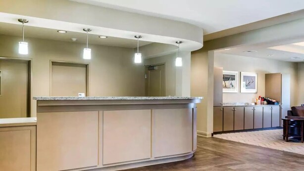Une cuisine moderne dotée d’un îlot central aux lignes courbes, d’un éclairage suspendu et d’un plancher en bois.