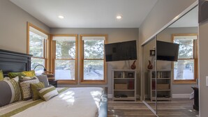 Un dormitorio con una cama grande, un televisor montado en la pared y una estantería.