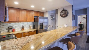 Una cocina moderna con encimeras de granito, electrodomésticos de acero inoxidable y armarios de madera.