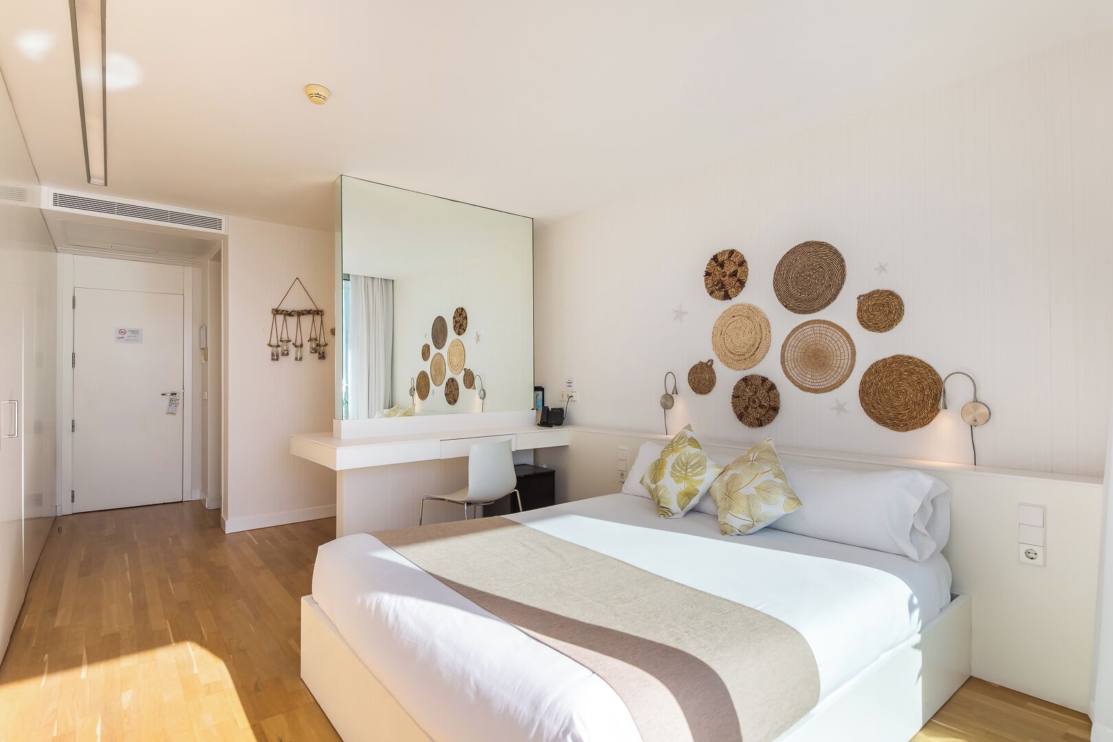 Un dormitorio moderno con una cama grande, un escritorio y una pared decorada con cestas tejidas.