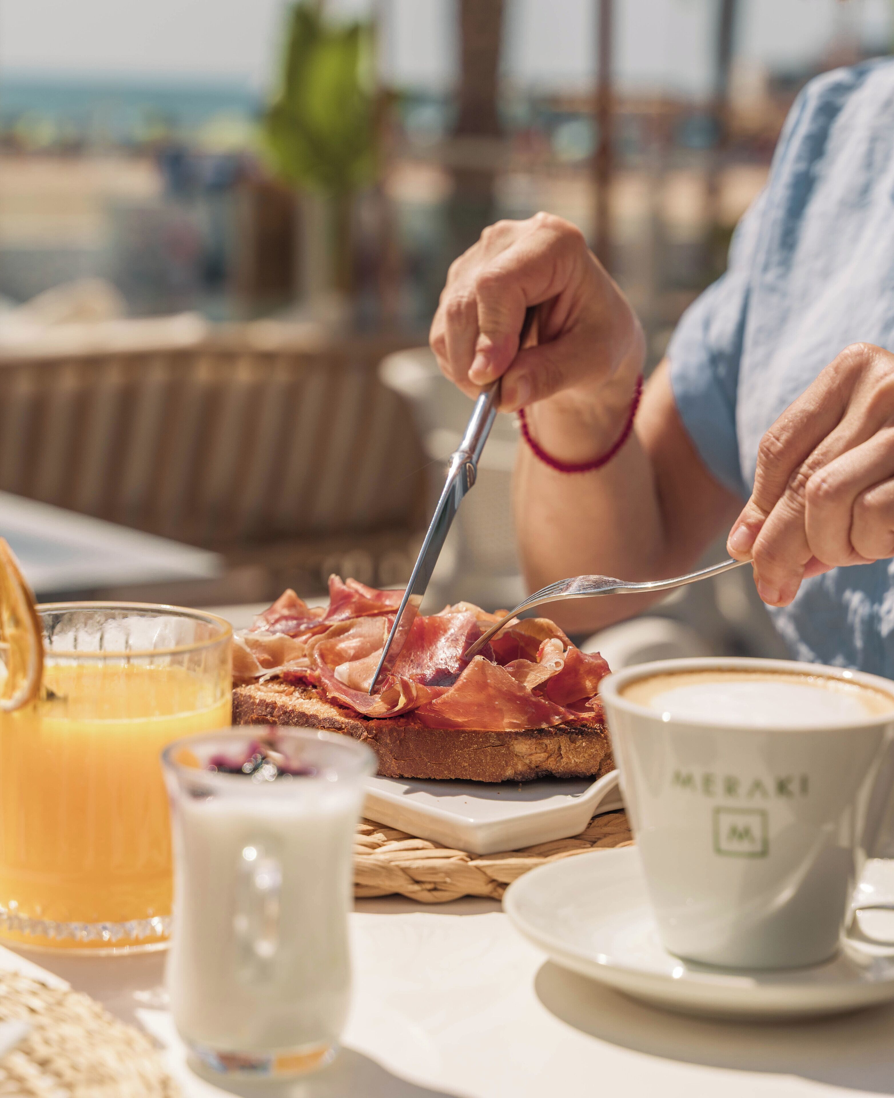 A breakfast setting with toast, ham, a cup of coffee, and a glass of orange juice.