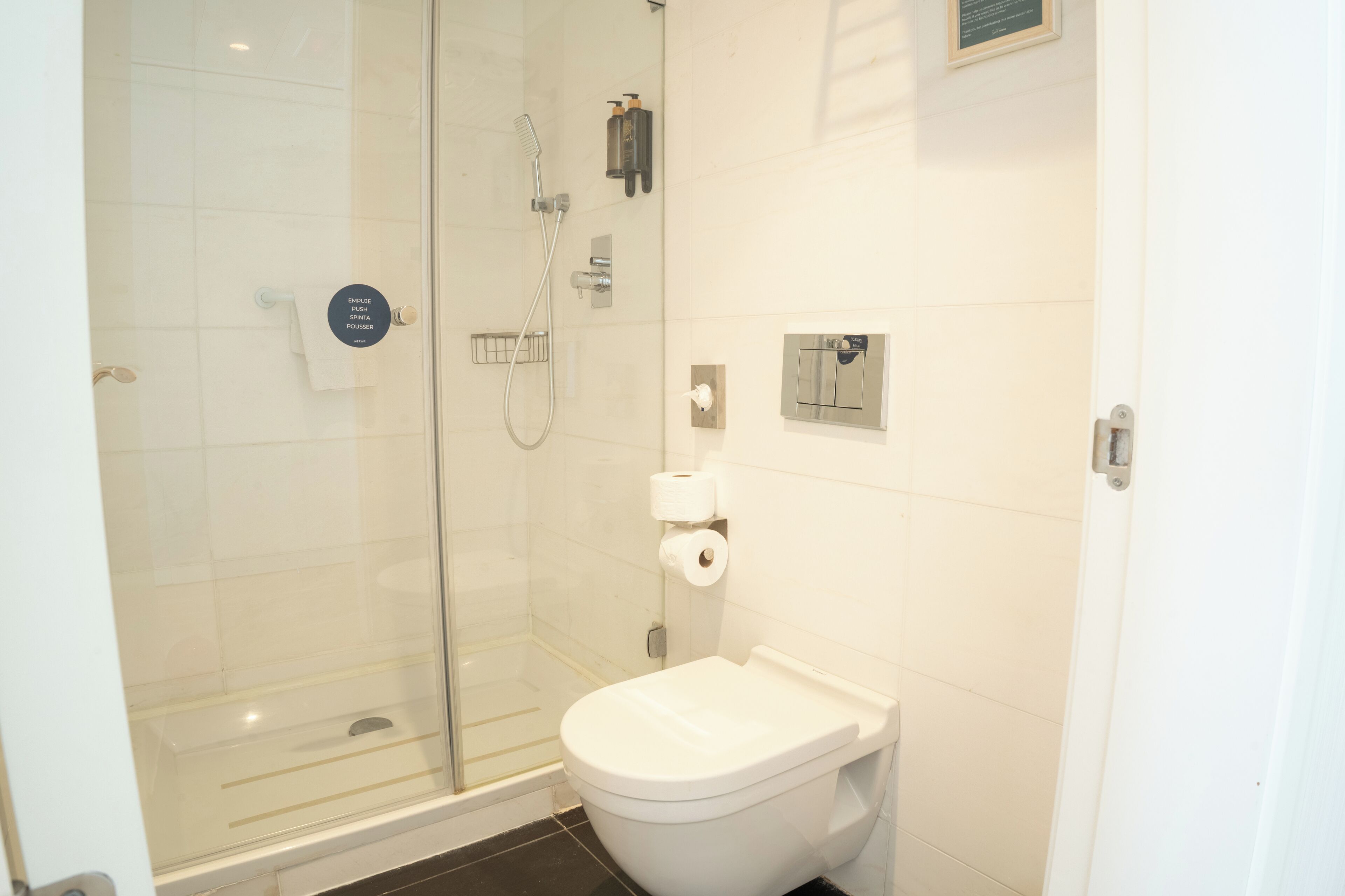 Un baño moderno con ducha acristalada, inodoro y toallero.