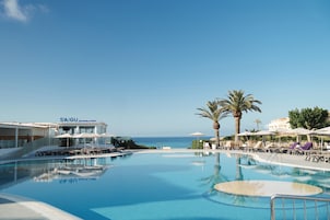 Una piscina al aire libre, sombrillas, sillones reclinables de piscina
