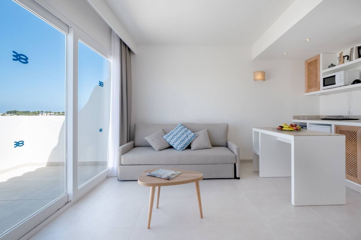 Una sala de estar moderna con un sofá, una mesita redonda y una cocina con microondas.