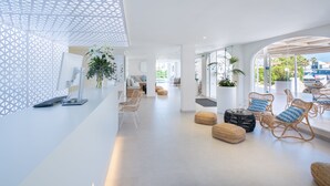 Rebost d'hotel modern, amb decoració en blanc, mobles de vimet i grans finestres que donen vistes a l'exterior.