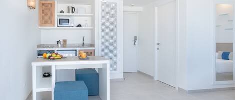 Una cocina moderna y minimalista con armarios blancos, microondas integrado y un frutero sobre la encimera.