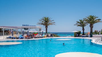 Una piscina al aire libre, sombrillas, sillones reclinables de piscina