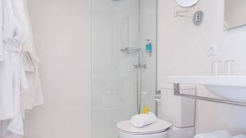 A modern bathroom with a glass shower enclosure, a white toilet, a sink with a mirror, and a towel rack.