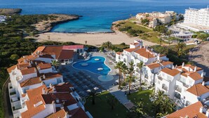 Un complex turístic amb piscina, platja i vistes a l'oceà.