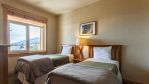 A hotel room with two beds, a window with a view of mountains, a lamp, and a framed picture on the wall. - Sunstone 329 (Mammoth Lakes)