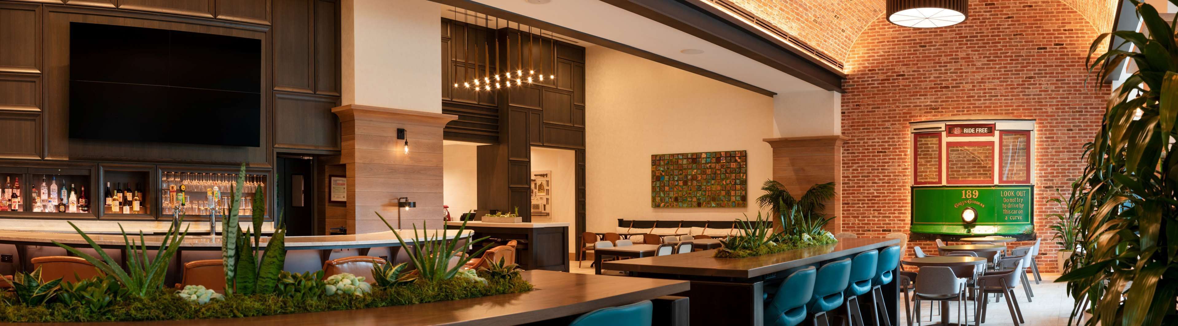 Un restaurant moderne doté d’un bar, de tables et d’un mur en briques.
