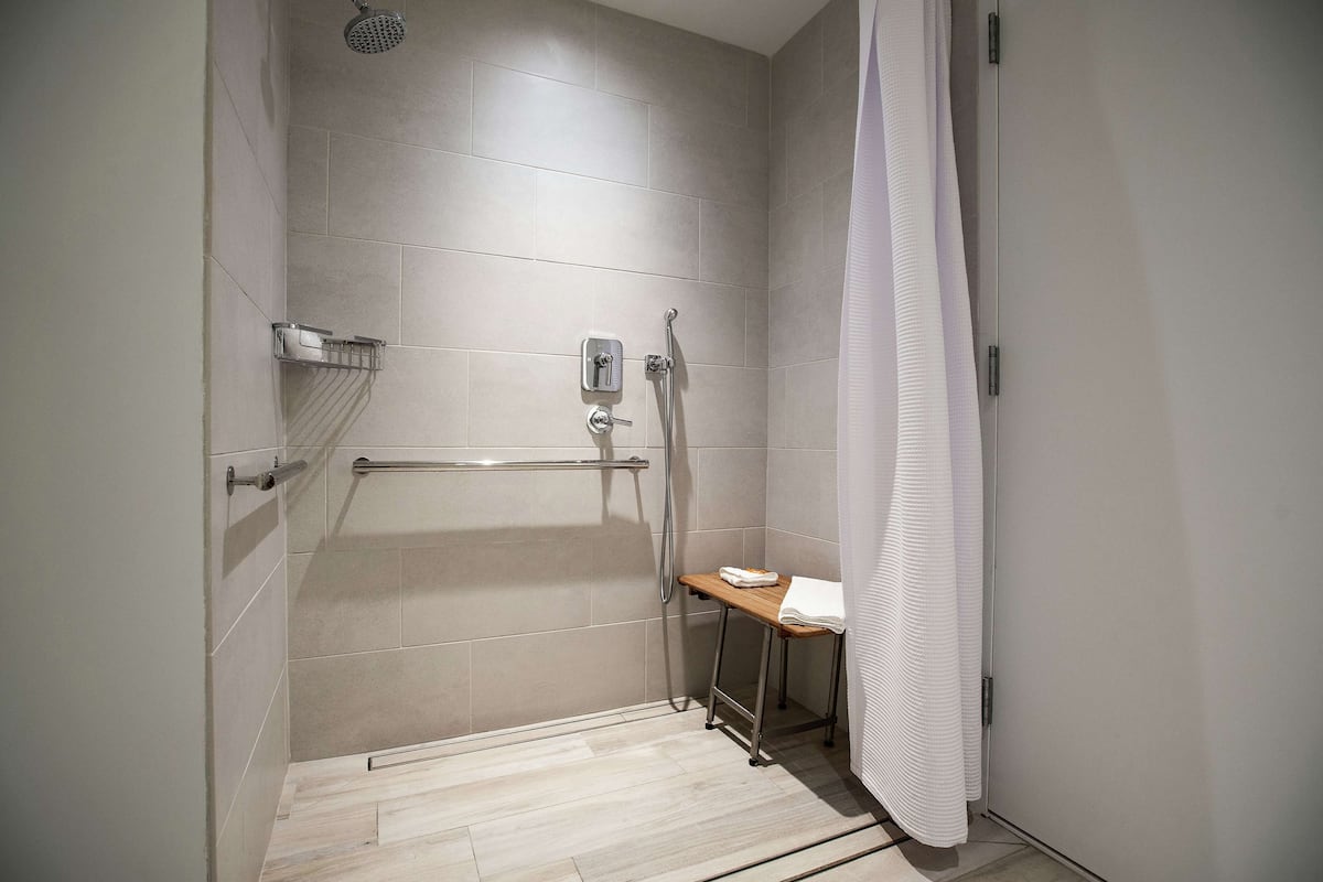 A modern bathroom with a shower, a toilet, and a small table with a towel.