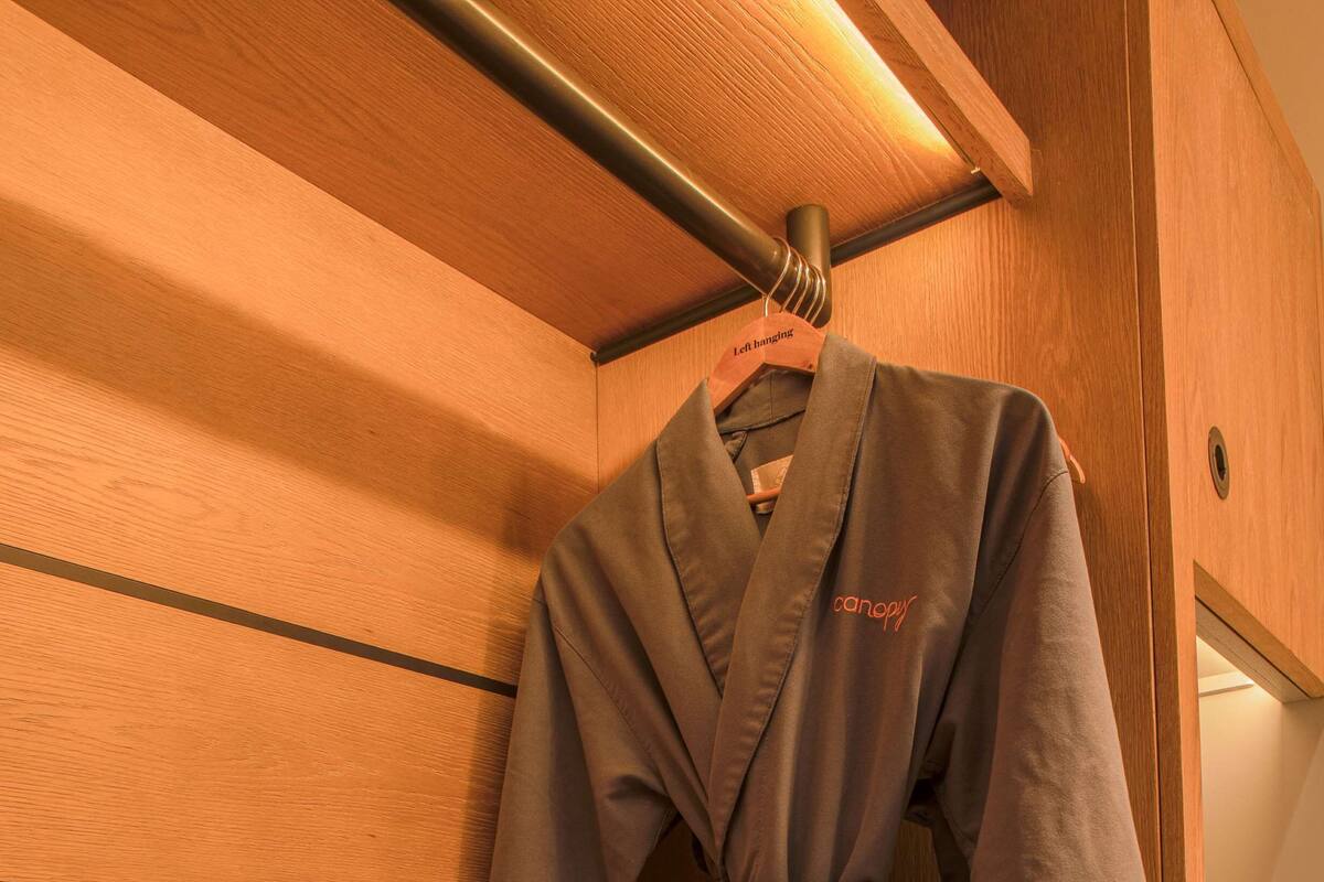 A wooden vanity with a robe hanging on a rack, a towel, and a note on the counter.