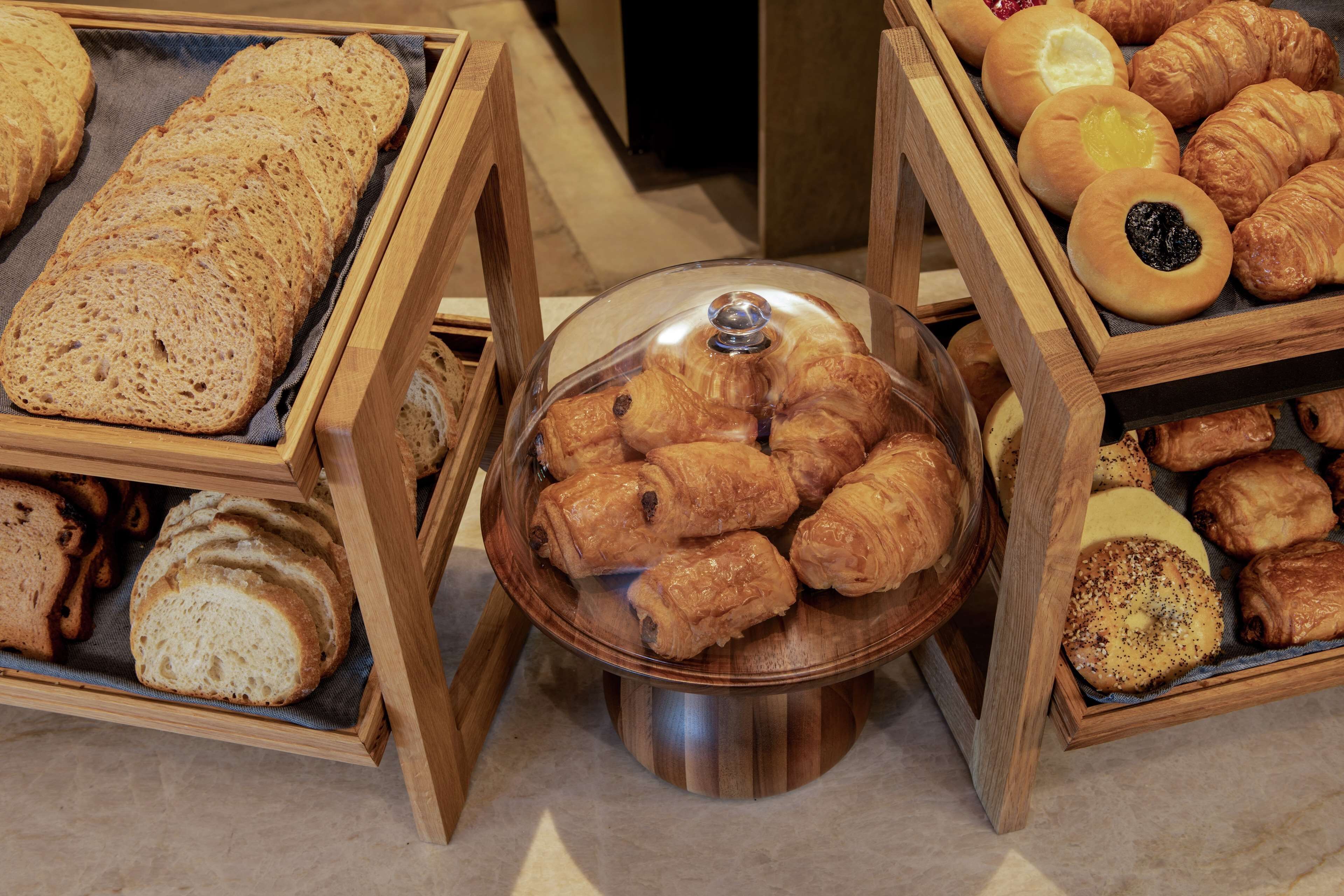A display of various breads and pastries in wooden stands.
