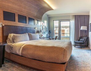 A hotel room with a large bed, a desk, a chair, and a view of the city through the window. - Canopy by Hilton Dallas Uptown (Dallas)