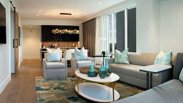 A modern living room with a sofa, armchairs, a coffee table, and a kitchen in the background.