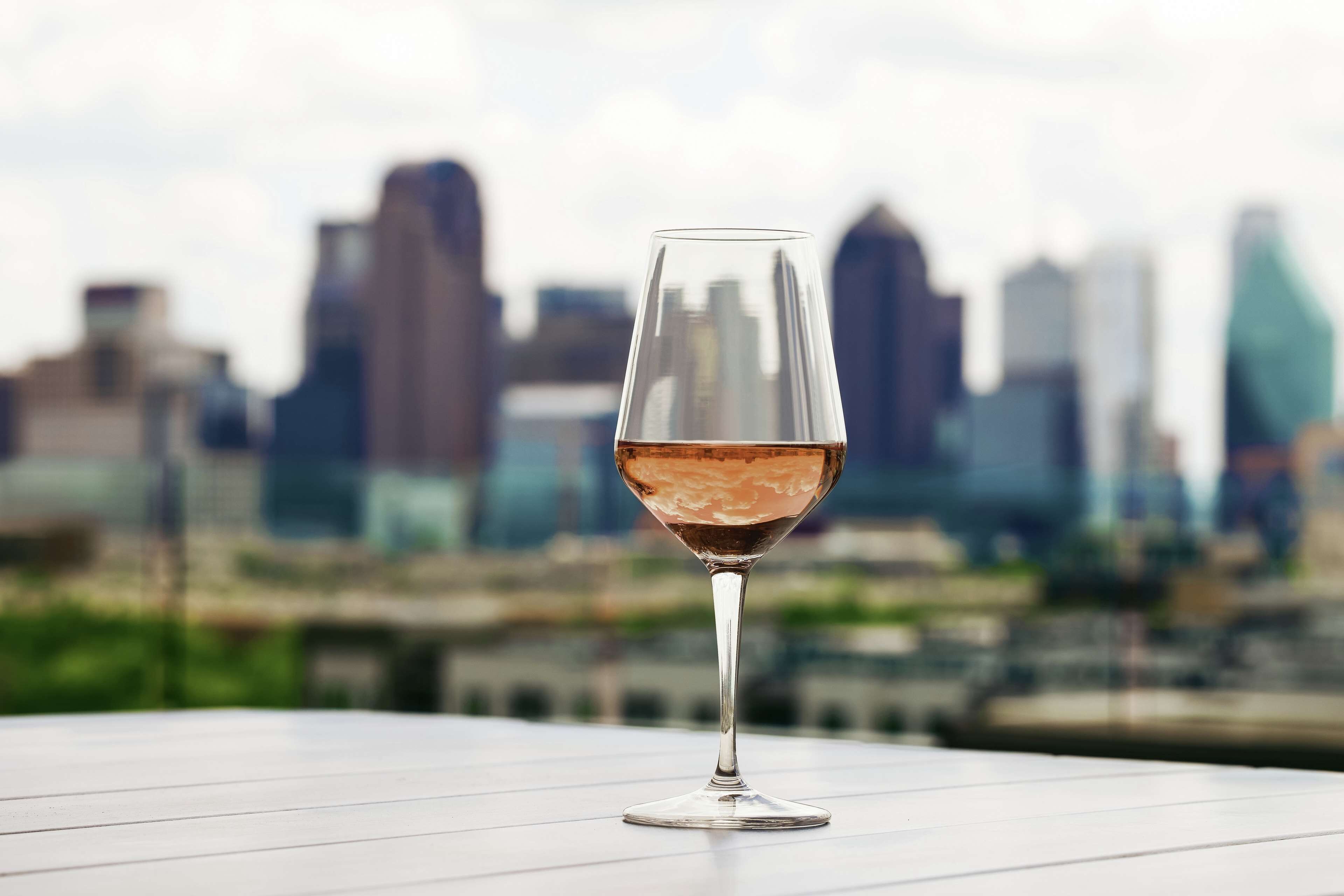 Una copa de vino sobre una mesa, con un horizonte urbano de fondo.