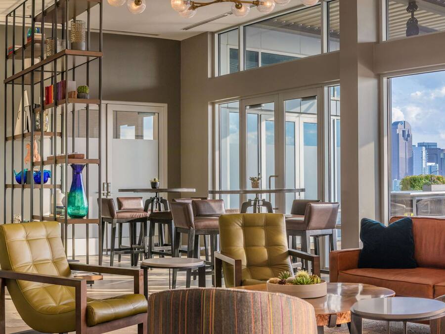 A modern lounge with leather seating, a glass partition, and a city view.