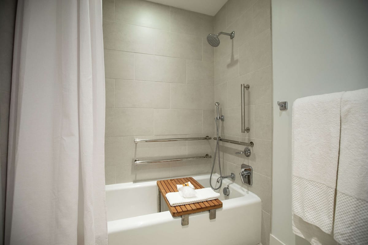 A modern bathroom with a bathtub, shower, and grab bars.