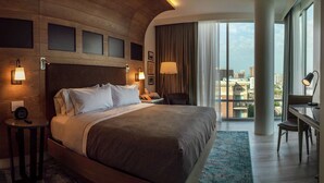 A modern hotel room with a large bed, a desk, and a view of the city. - Canopy by Hilton Dallas Uptown (Dallas)