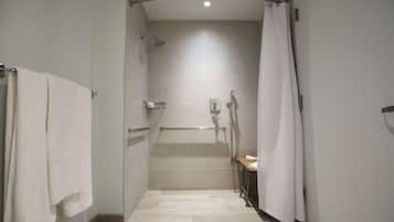 A modern shower area with a grab bar, a towel rack, and a showerhead.