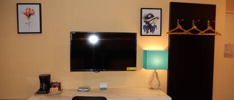 Une chambre d’hôtel équipée d’une télévision à écran plat, d’un bureau avec une lampe, d’un réfrigérateur et d’une chaise.