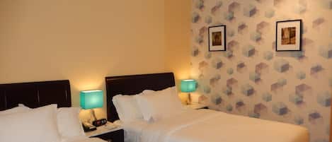 A hotel room with two beds, a nightstand with a lamp, and a patterned wall.