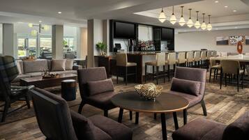 Eine moderne Lounge mit Sitzgelegenheiten, einer Bar und einem Fernseher.