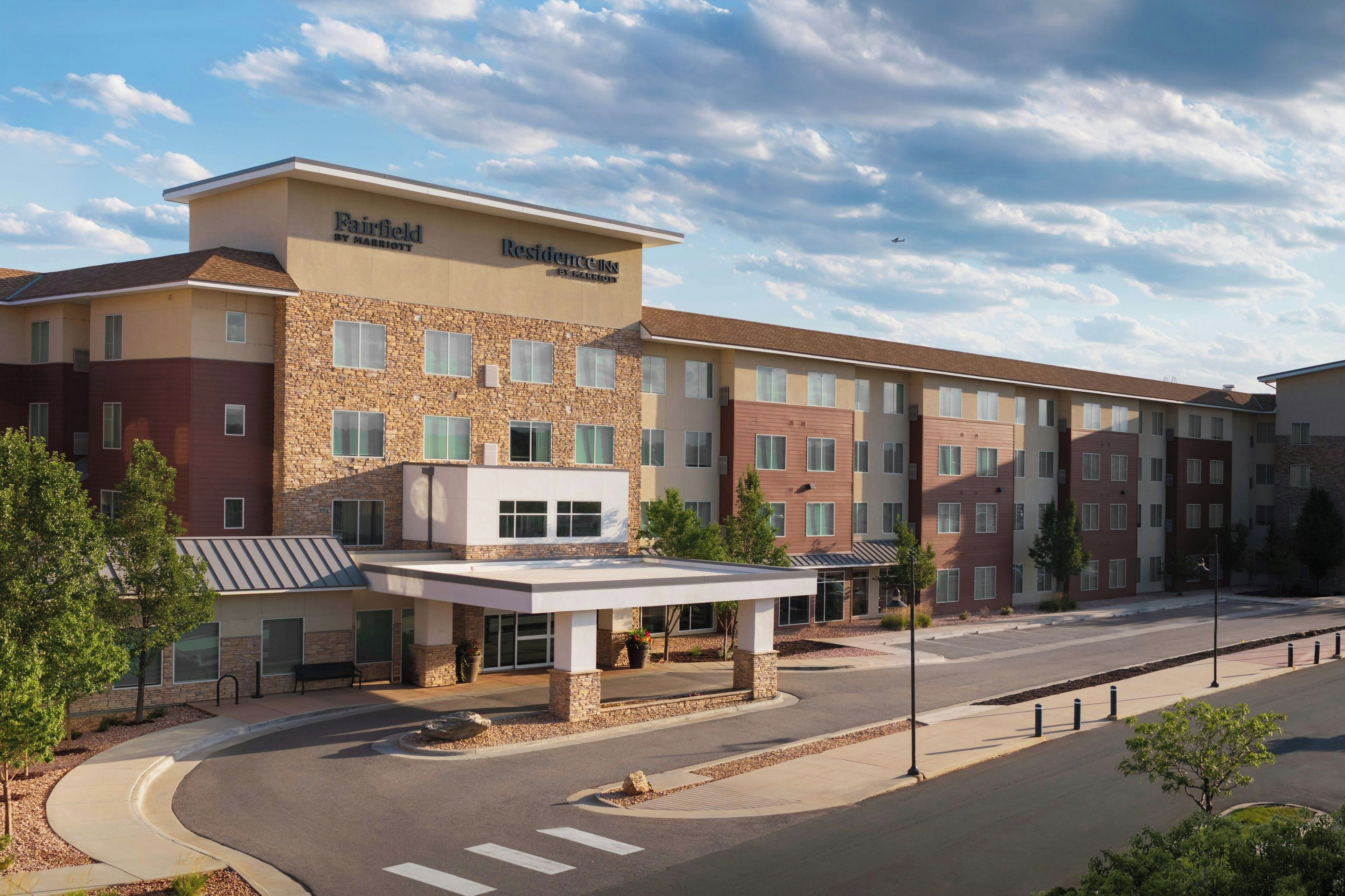 A multi-story hotel with a stone facade, a covered entrance, and a parking lot.