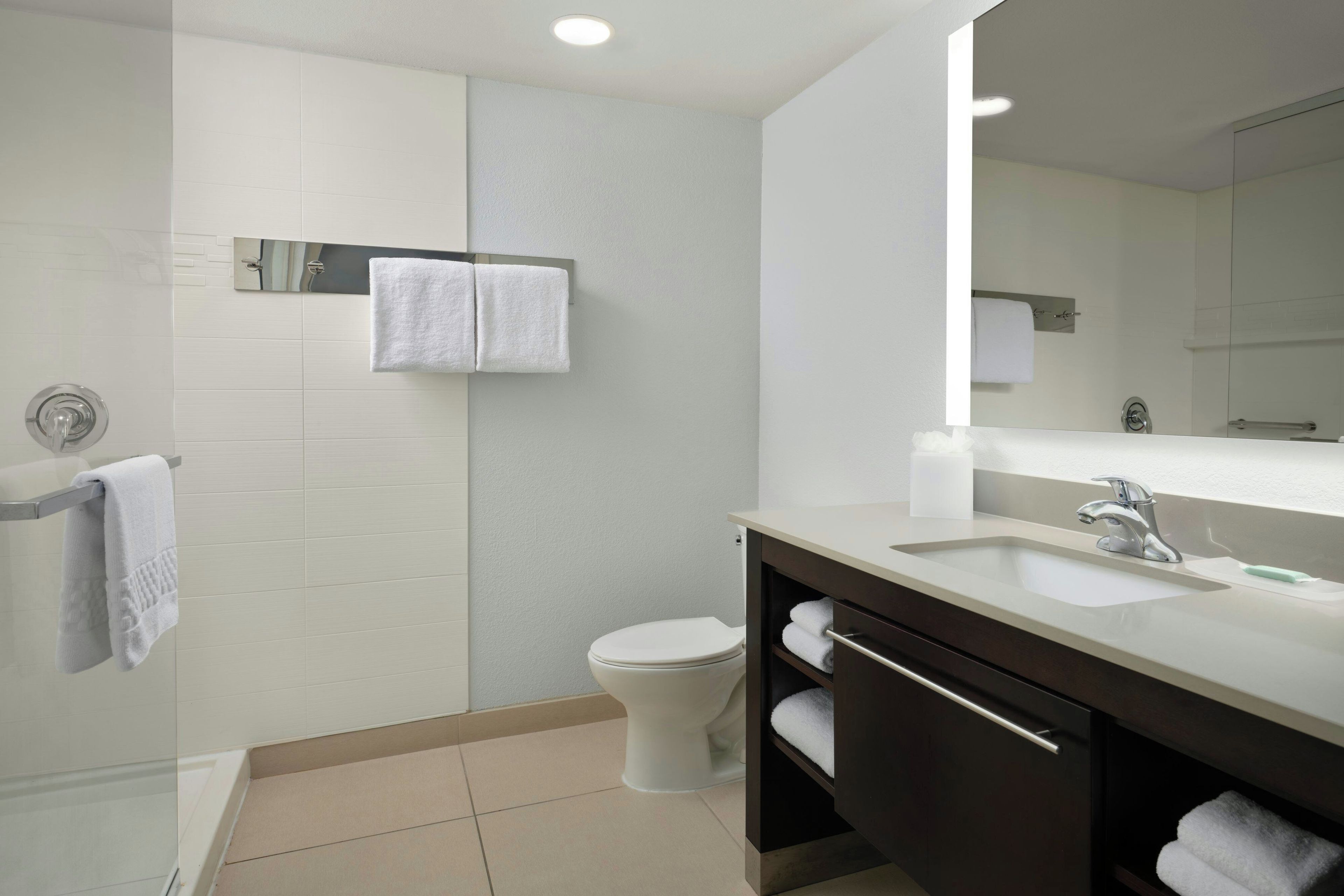 A modern bathroom with a toilet, a sink, a mirror, and a towel rack.