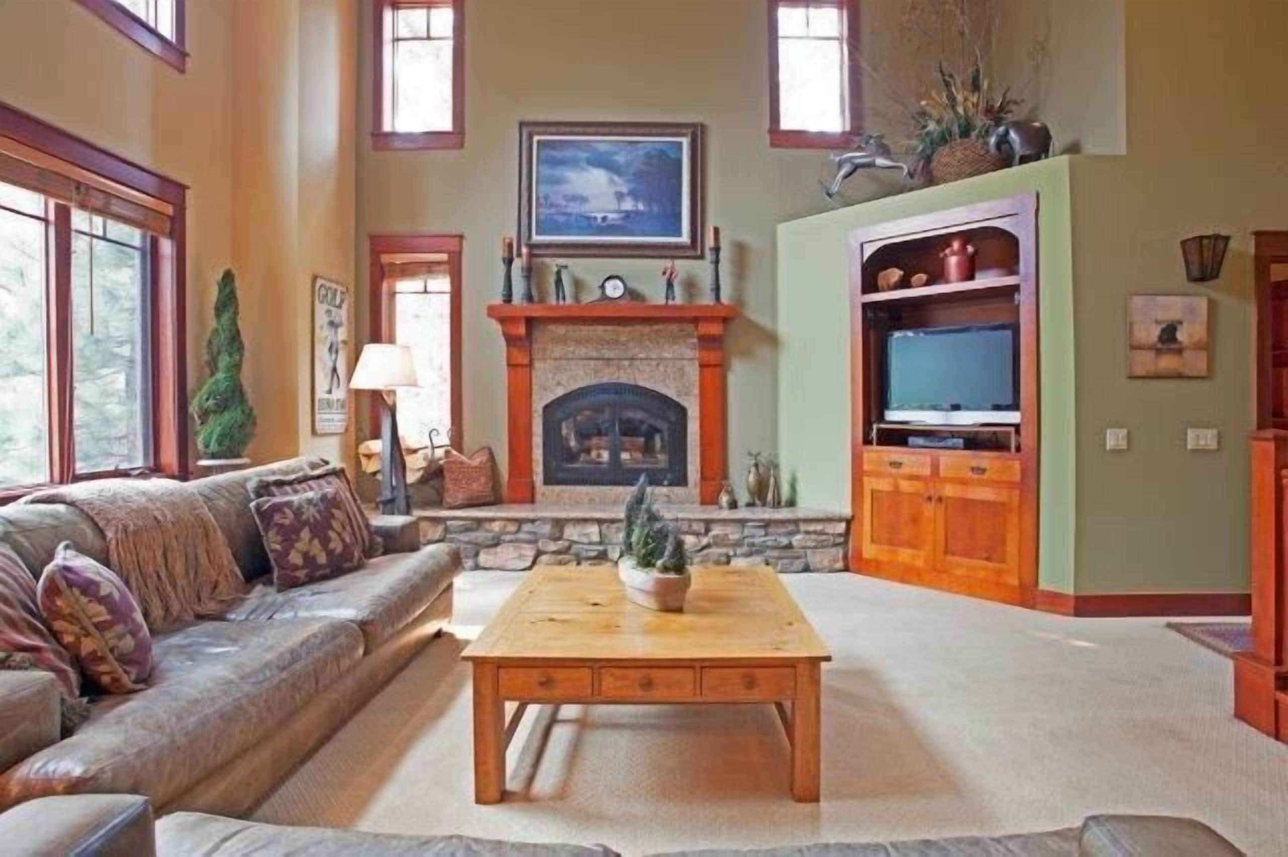 A cozy living room with a fireplace, a sofa, a coffee table, and a television.