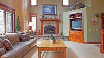 A cozy living room with a fireplace, a sofa, a coffee table, and a television.